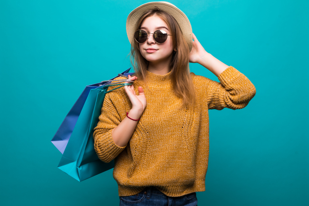 young-teen-woman-sunglasses-hat-holding-shopping-bags-her-hands-feeling-so-happiness-isolated-green-wall